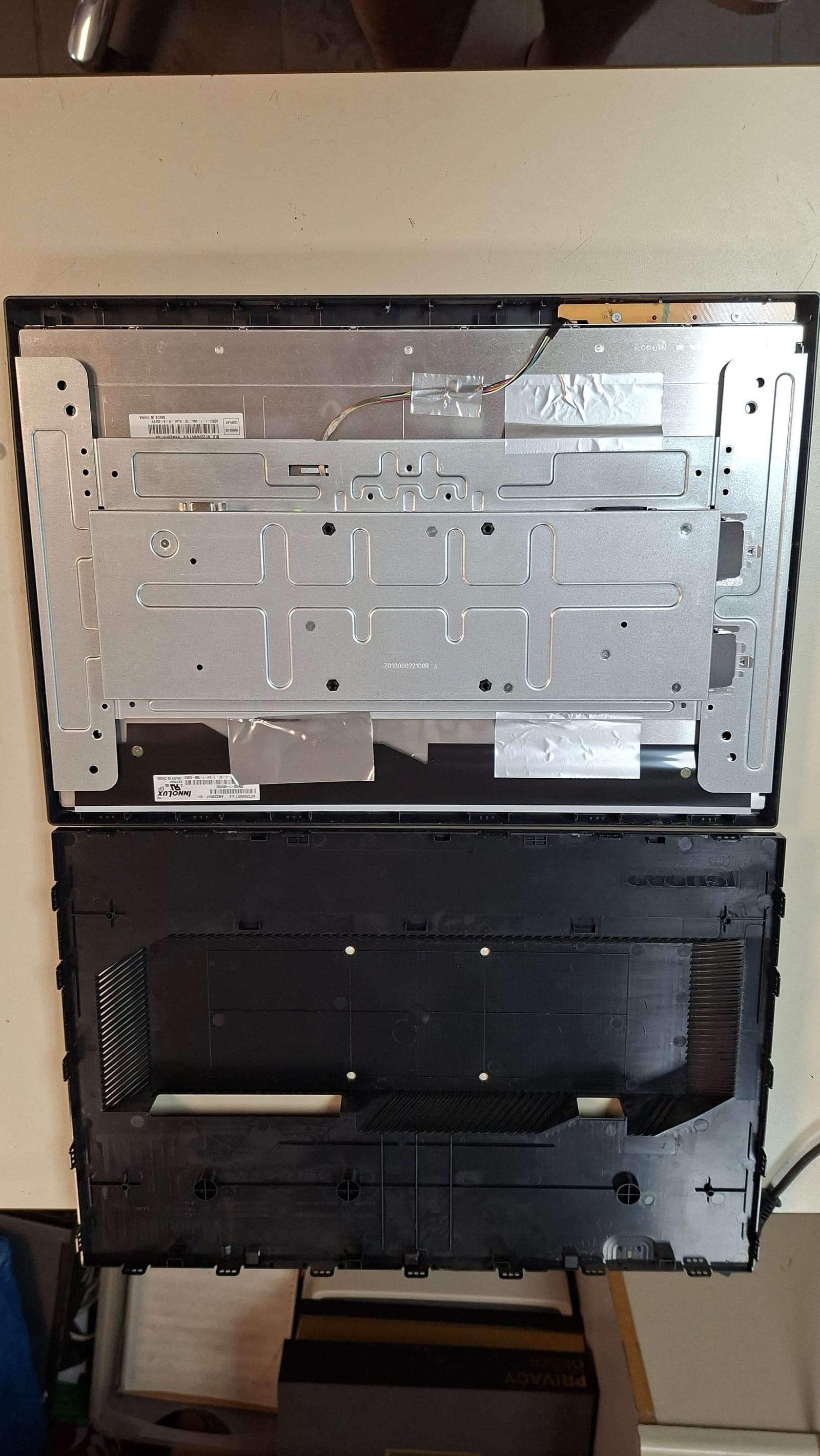Gehäuse geöffnet. Links die Plastik-Rückwand, rechts die Aluminium-Trägerplatte mit Klebestreifen und ursprünglichen Schraubpositionen.
